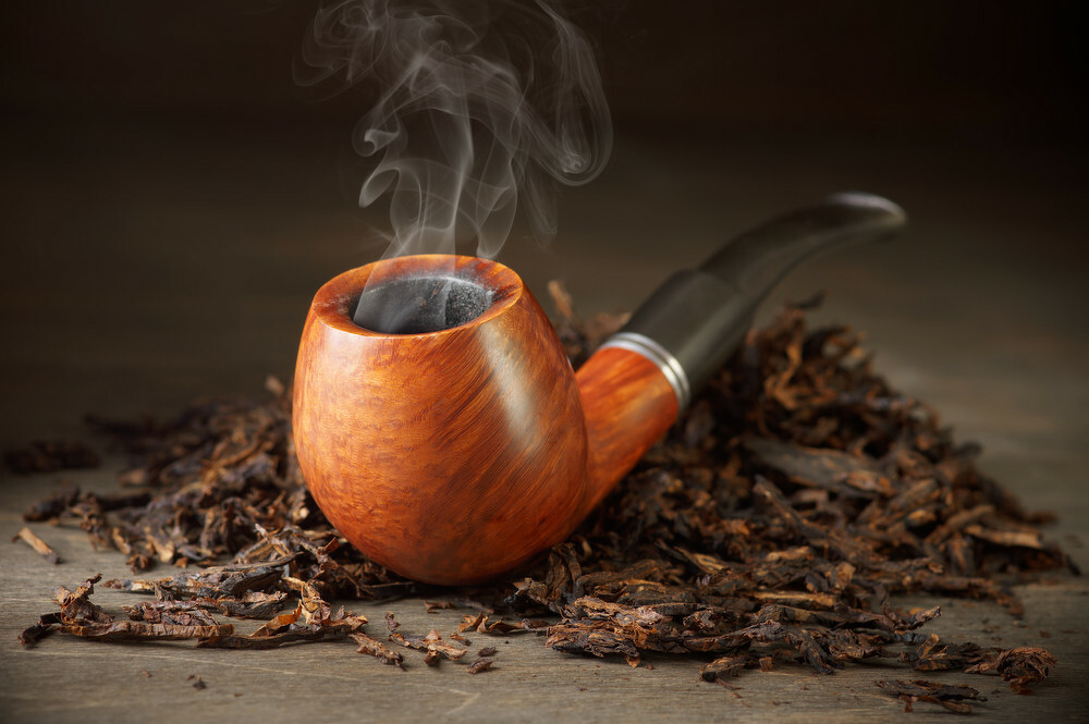 A picture of a smoking pipe laying on some tobacco
